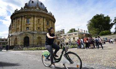 Woman on bike in front of the Radcliffe Cam